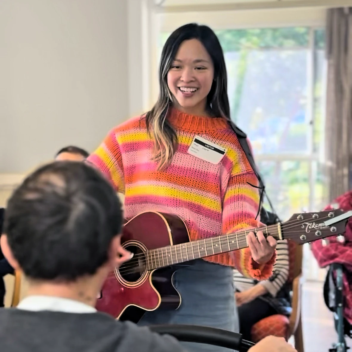 Flora smiling and playing guitar with a group